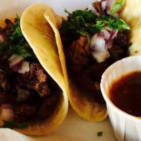 Tacos De Carne Azada · Three soft corn tortillas filled with steak, cilantro and onions. Served with rice, beans, l...