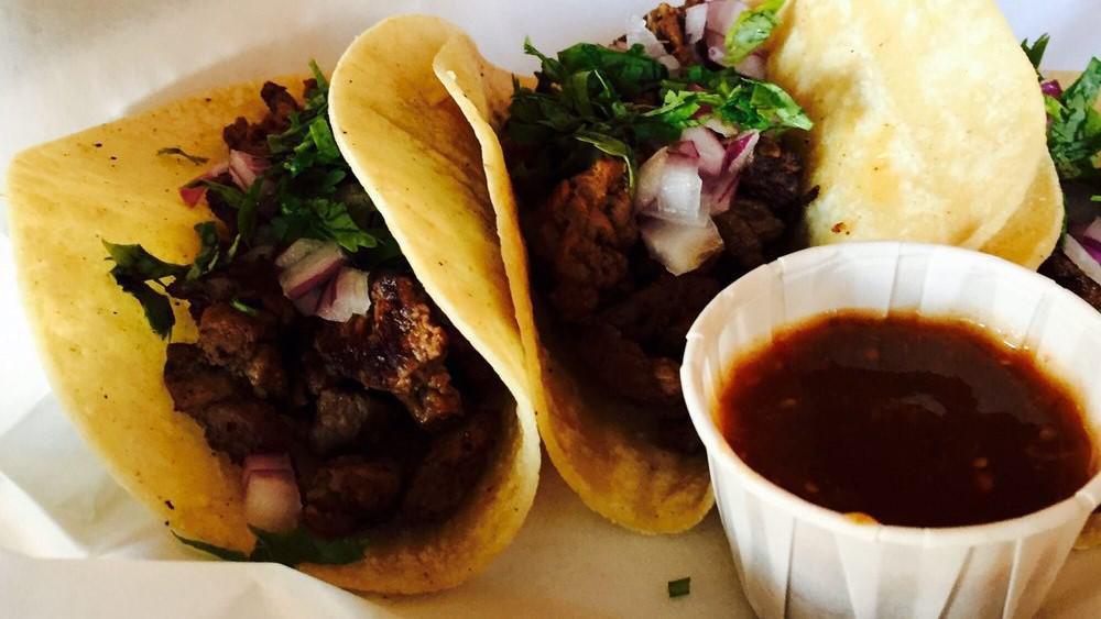 Tacos De Carne Azada · Three soft corn tortillas filled with steak, cilantro and onions. Served with rice, beans, lime and side of tomatillo sauce.
