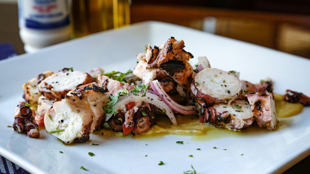 Octapodi · Braised sushi grade octopus, char-grilled, sliced and tossed in olive oil, parsley, red peppers, and herbs, served over a bed of fave puree and julienned sliced red onions.