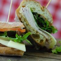 Turkey And Swiss Sandwich · Wood smoked turkey, Swiss cheese, fresh greens, tomatoes, and date mustard.