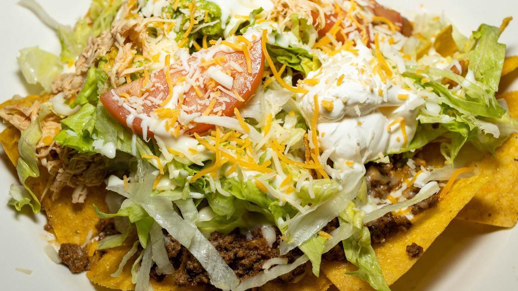 Nachos Supreme · Nachos with cheese, beef, chicken and beans, topped with lettuce, tomatoes, sour cream and guacamole.