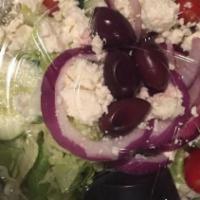 Greek Salad · Crisp iceberg lettuce topped with crumbled feta cheese, stuffed grape leaves, kalamata olive...