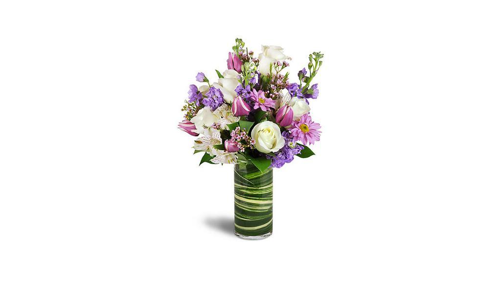 Smiling Grace · Bright purple hues pop among creamy white blooms for a stunning display! For a birthday, anniversary, or just because - sure to bring smiles to your special someone. White roses and alstroemeria are complemented with purple tulips, stock, and daisies in a chic leaf-lined glass vase. Product ID UFN1499. Approximately 12