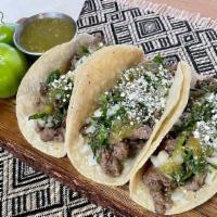 Angus Steak Tacos · Three tender steak tacos served with white onions, cilantro, lime wedges, topped with cheese...