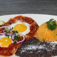 Huevos Rancheros · Three crispy corn tortillas topped with tomato salsa, two sunny up eggs served with rice and...