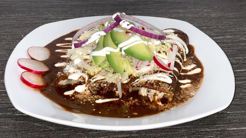 Enchiladas Poblanas · Three soft corn tortillas, topped with mole poblano, sour cream, cotija cheese, lettuce, onions and avocado. Served with rice and beans.
