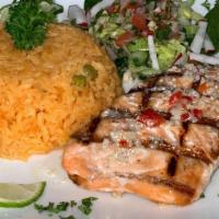 Salmon A La Parrilla · Grilled salmon served with salad, rice and beans.