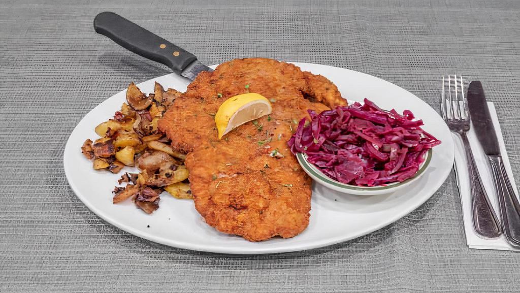 Wiener Schnitzel · Breaded and fried pork cutlet, with lemon wedge on the side, and served with home fried potatoes and red cabbage.
