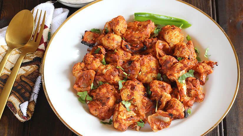 Tandoori Gobi · GLUTEN FREE - Tender florets of cauliflower, onions, bell pepper are coated and marinated in yogurt & with chef special spices and roasted in a cylindrical Indian clay oven.