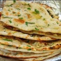 Garlic Naan · Made with white flour mix with milk, yeast & salt coated with butter & garlic cooked in char...