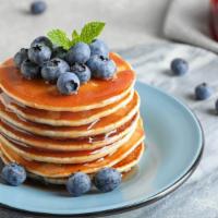 Blueberry Pancakes · Shortstack of fluffy blueberry pancakes topped with maple syrup.