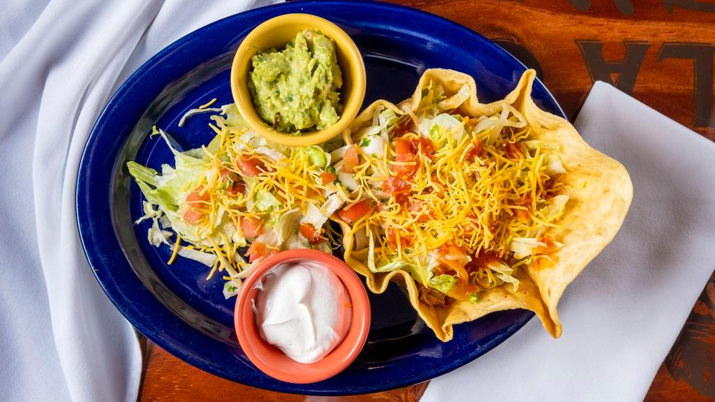 Traditional Taco Salad · A crispy flour shell stuffed with shredded chicken, ground beef or shredded beef, iceberg lettuce, tomatoes, shredded Jack and Cheddar cheese, mild sauce, guacamole, and sour cream.