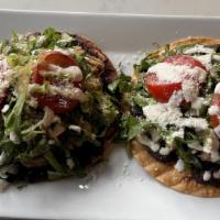 Mexican Tostadas · Two fried corn tortillas topped with refried beans, shredded lettuce, sour cream, tomato, sl...