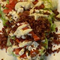 Iceberg Wedge Salad · Iceberg wedge topped with bacon, tomato, and blue cheese crumbles with blue cheese dressing.