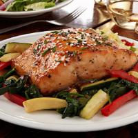 Pan-Seared Asian Salmon · Pan-seared salmon brushed with an orange ginger glaze. Served over a bed of vegetables and a...