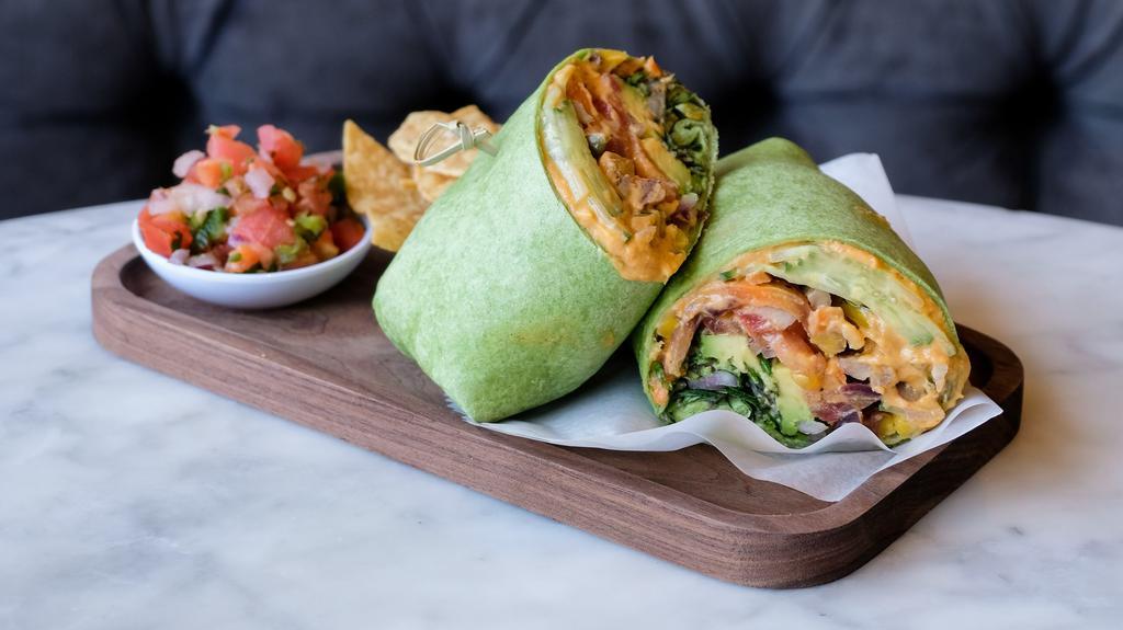 Vegan Veggie Wrap · Spicy hummus, sliced avocado, tomatoes, roasted carrots, cucumbers, red onion, baby kale, sprouts and pumpkin seeds on a spinach wrap