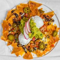 Nachos Regulares · Served with jack and Cheddar cheese, black beans, sour cream, jalapeños, guacamole and pico ...