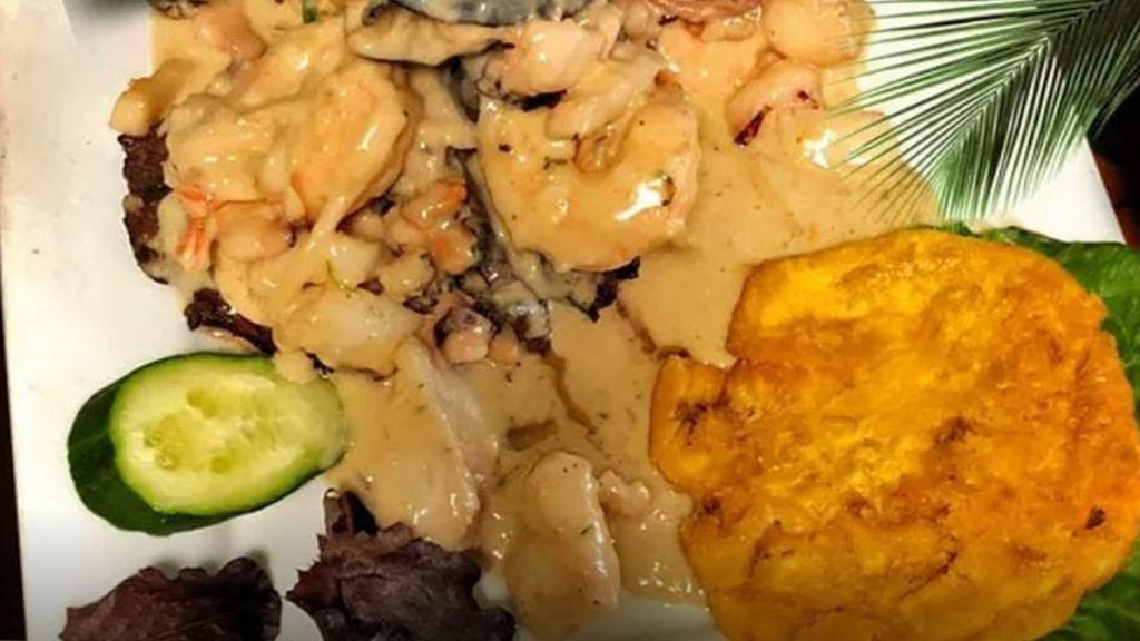 Churrasco Amarinado Con Arroz, Ensalada Y Tostones · Sirloin steak topped with seafood with rice, salad and fried green plantains.