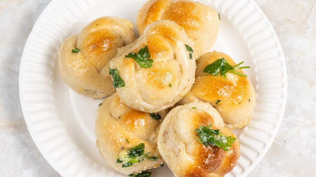 Garlic Knots 6 · A classic snack, our garlic knots are strips of pizza dough tied in a knot, baked, and then topped with melted butter, garlic, and parsley.