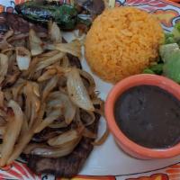Steak With Onions / Bistec Encebollado · Served with rice, beans, and three tortillas. / Acompañado con arroz, frijoles y tres tortil...