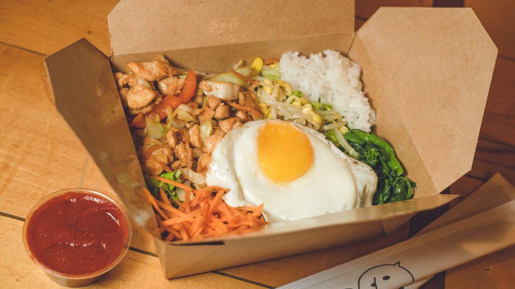 Chicken Bibimbap · Traditional Korean rice bowl with lightly seasoned and sautéed vegetables and chicken, topped with a sunny egg. Served with gochujang (sweet and spicy chili pepper paste) and an assortment of traditional side dishes (banchan).