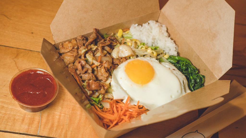 Pork Bibimbap · Traditional Korean rice bowl with lightly seasoned and sautéed vegetables and pork, topped with a sunny egg. Served with gochujang (sweet and spicy chili pepper paste) and an assortment of traditional side dishes (banchan).