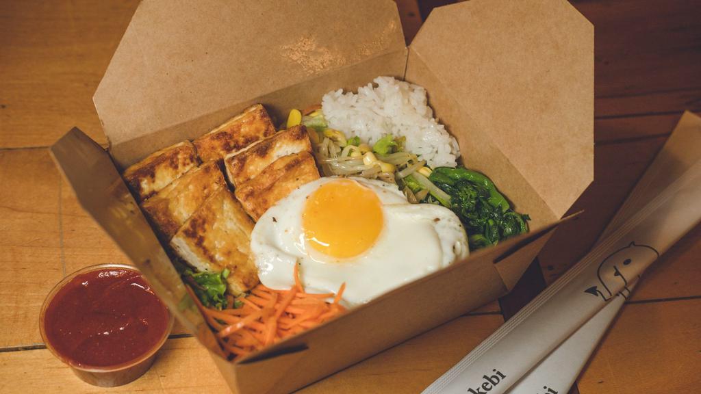Fried Tofu Bibimbap · Traditional Korean rice bowl with lightly seasoned and sautéed vegetables and tofu, topped with a sunny egg. Served with gochujang (sweet and spicy chili pepper paste) and an assortment of traditional side dishes (banchan).