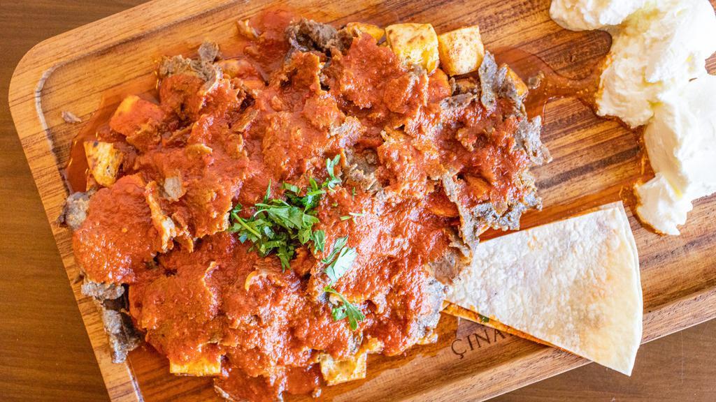 Traditional Iskender Kebab · Served Thinly cut grilled doner kebab over Turkish Bread pieces and yogurt mix, topped with hot tomato sauce. Not served with rice or veggies. rice, salad and white sauce.