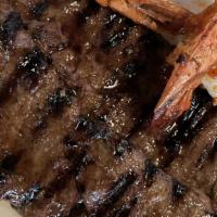Surf And Turf · Skirt steak, topped with grilled shrimps. Served with rice and beans.