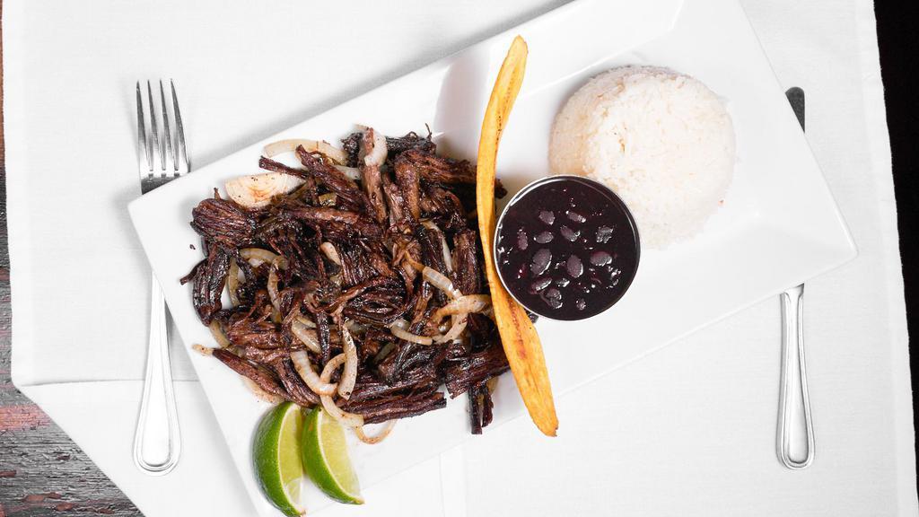 Vaca Frita · Pan-fried shredded skirt steak flavored with mojo criollo sauce. Served with black beans and white rice.