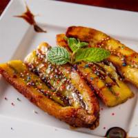 Platano De Feria · Fried sweet plantains serve with chocolate syrup and caramel on top