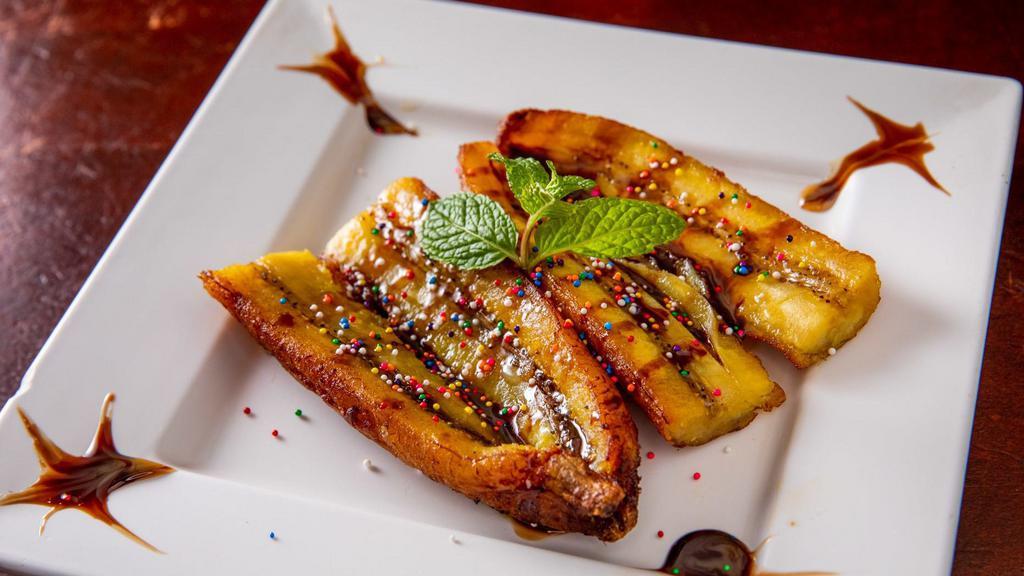 Platano De Feria · Fried sweet plantains serve with chocolate syrup and caramel on top
