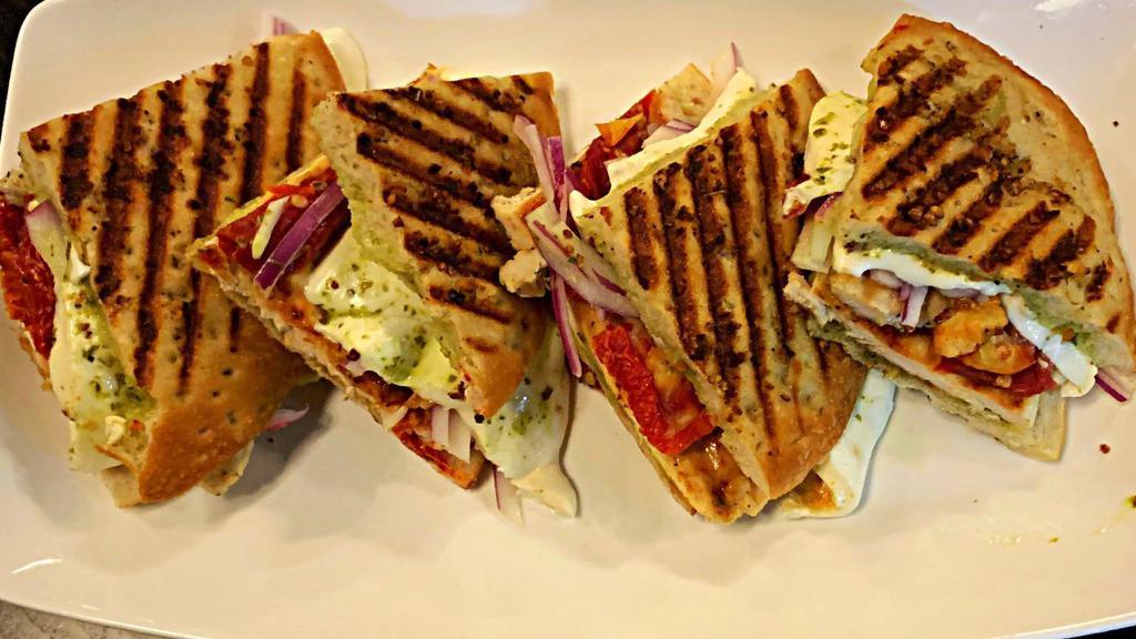 Grilled Chicken Panini · Grilled Chicken with melted Fresh Mozzarella, Sun dried Tomatoes, Red Onion & Creamy Pesto in our Homemade Panini Bread.