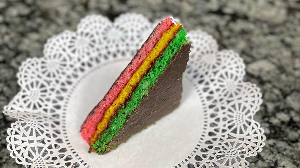Rainbow Cookie Slice · Our famous rainbow cookie in a big cake slice! Made with almond paste and raspberry filling.