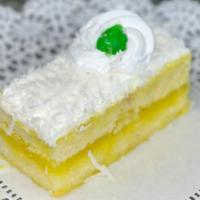 Lemon Coconut Slice · Vanilla sponge layered with lemon filling, topped with fresh whipped cream and coconut flakes.