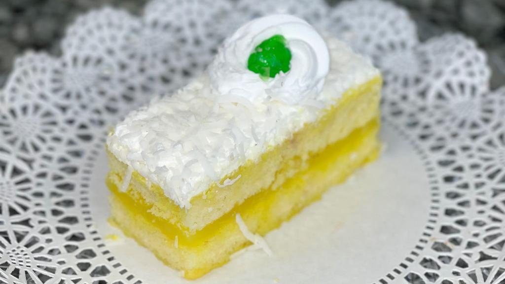 Lemon Coconut Slice · Vanilla sponge layered with lemon filling, topped with fresh whipped cream and coconut flakes.