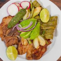 Chuletas Asadas Con Nopales Y Cebollitas · Grilled pork chops with cactus and scallions served with rice and beans, and tortillas or br...
