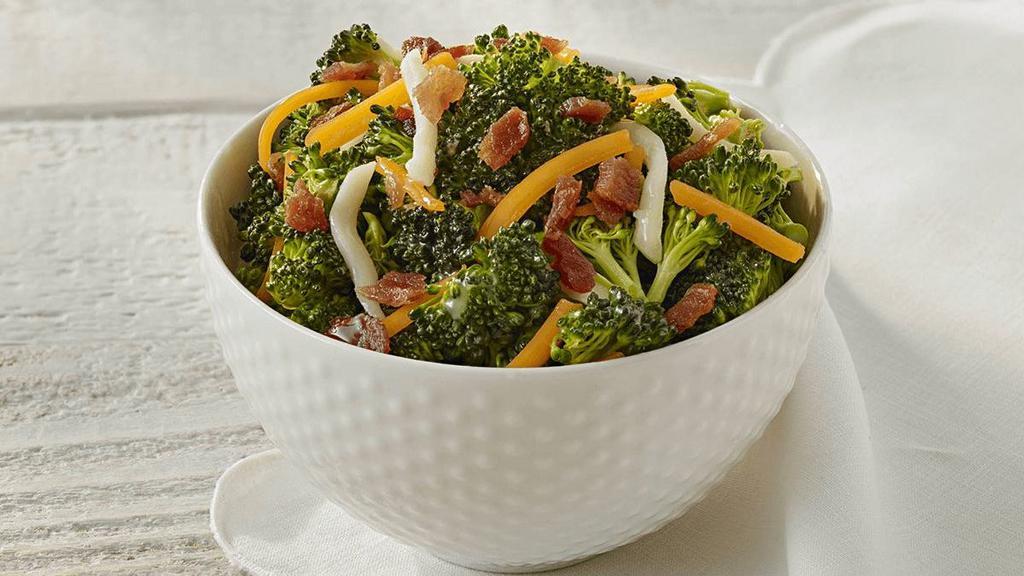 Broccoli Salad · Fresh broccoli florets tossed in a sweet vinegar-based dressing with shredded mozzarella & cheddar cheeses, topped with crispy bacon.