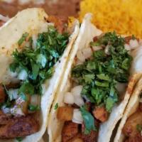 Tacos Al Pastor · Specially marinated strips of pork grilled with pineapples. Topped with cilantro and onions....