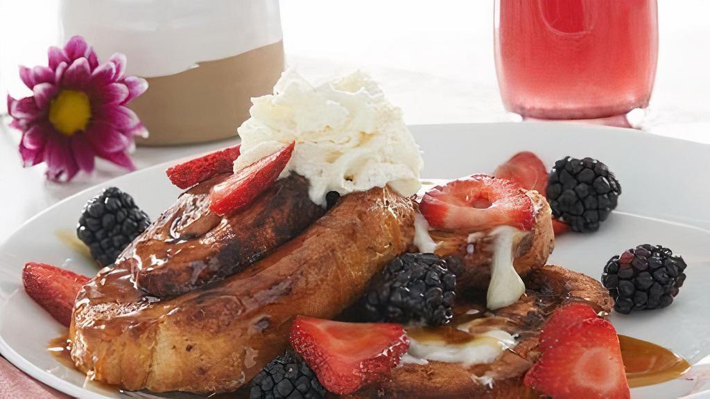 Cinnamon Roll French Toast · Thick-sliced, house-baked French-toast style cinnamon rolls topped with cream cheese icing, rum butter sauce drizzle, fresh seasonal berries and whipped cream.