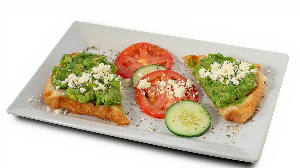 Avocado Toast · Avocado spread on waffled sourdough bread served with cucumber, tomato, feta, and dusted with oregano.