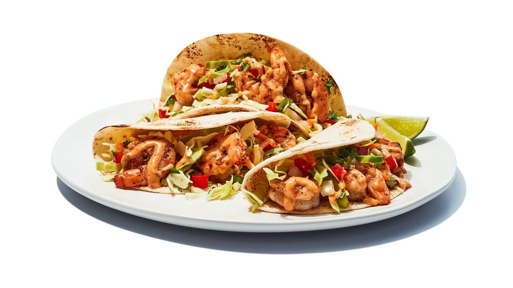 Baja Shrimp Tacos · Baja Shrimp Tacos - We grill seasoned shrimp, then wrap them in flour tortillas with an un-shrimp amount of cabbage, diced tomatoes and special sauce.  Welcome to flavor beach.
