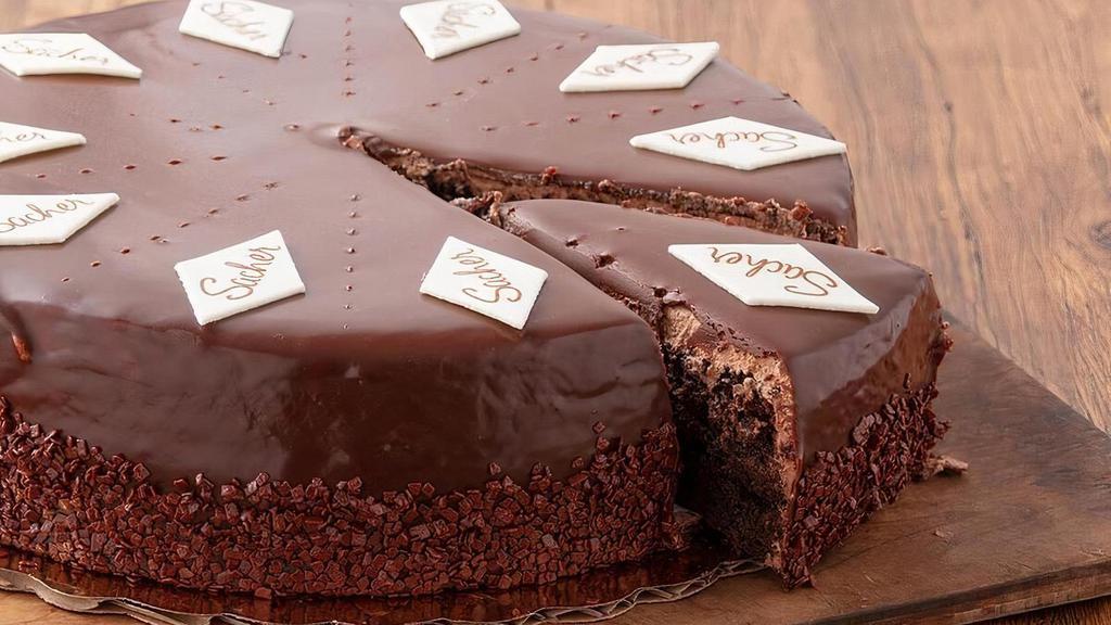 Whole Sacher Torte · Three chocolate cake layers soaked with vanilla syrup and filled with a thin layer of raspberry jam finished with chocolate mousse topping.  Enrobed in rich chocolate ganache and topped with our traditional Sacher candy emblems.