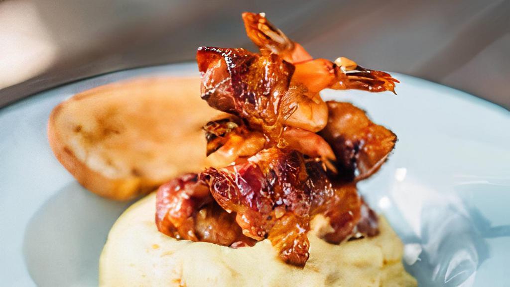 Voodoo Shrimp And Grits · Chargrilled jumbo gulf shrimp stuffed with cream cheese, pickled jalapeños, wrapped in bacon, tossed in sweet chili glaze, served with corn grits and garlic bread