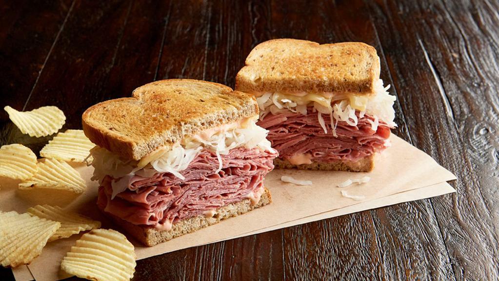 Reuben The Great Regular · 1/2 pound of hot corned beef, Swiss, sauerkraut, 1000 Island dressing, grilled on marbled rye. Served with chips or baked chips (150/100 cal) and a pickle (5 cal).