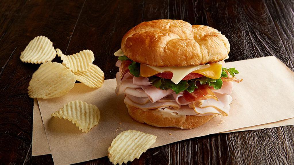 Club Royale Regular · Nitrite-free smoked turkey breast and ham, bacon, Swiss, cheddar, leafy lettuce, tomato, honey mustard, on a toasted croissant. Served with chips or baked chips (150/100 cal) and a pickle (5 cal).