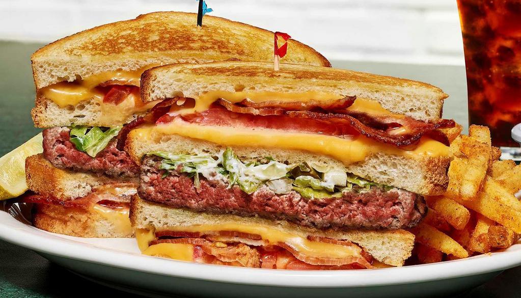 Holy Davoli · 100% Angus burger topped with pickle slaw (shredded lettuce, chopped pickle and mayonnaise) in between two grilled cheese sandwiches stuffed with American cheese, tomato, and hickory smoked bacon.