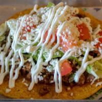Tostada · Flat crunchy tortilla with ground beef refried beans lettuce tomatoes sour cream and queso f...