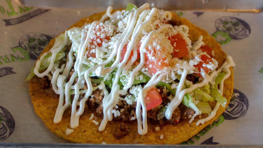 Tostada · Flat crunchy tortilla with ground beef refried beans lettuce tomatoes sour cream and queso fresco.