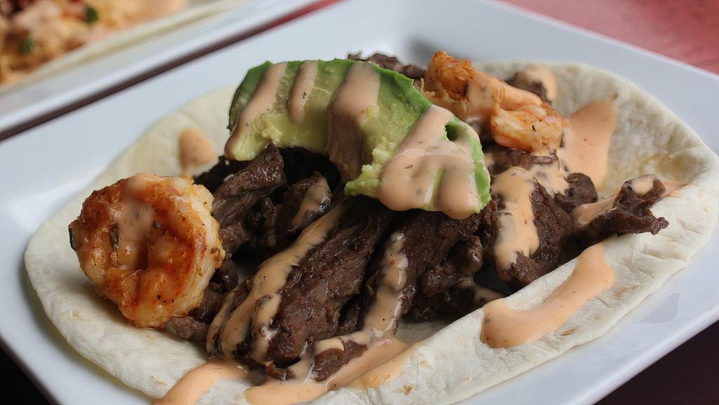 Surf & Turf · Skirt steak and shrimp topped with avocado and sriracha ranch. Served in a flour tortilla.